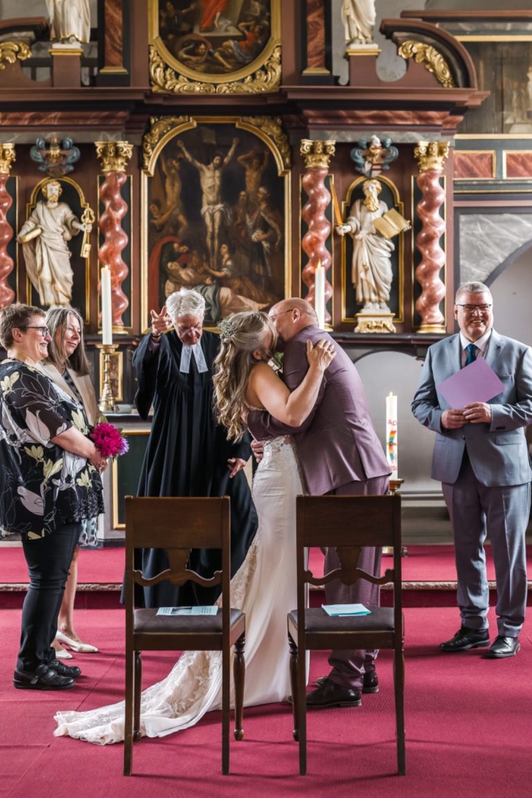 Braut und Bräutigam küssen sich während der Zeremonie in einer Kirche.